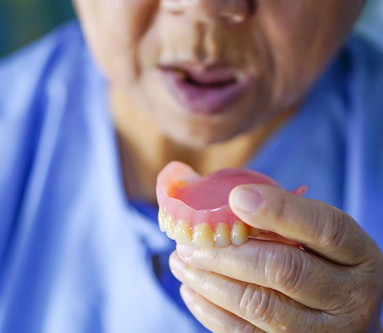 Dentist holding a full denture