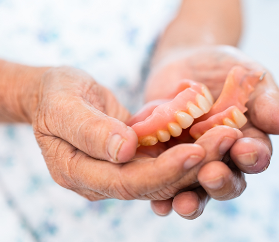 Close up of hands holding full dentures