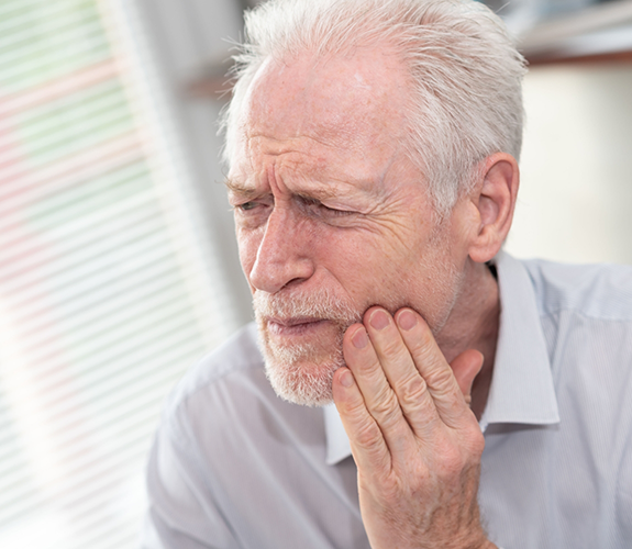 Older man rubbing his jaw in pain