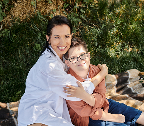 Dental team member hugging little boy with glasses