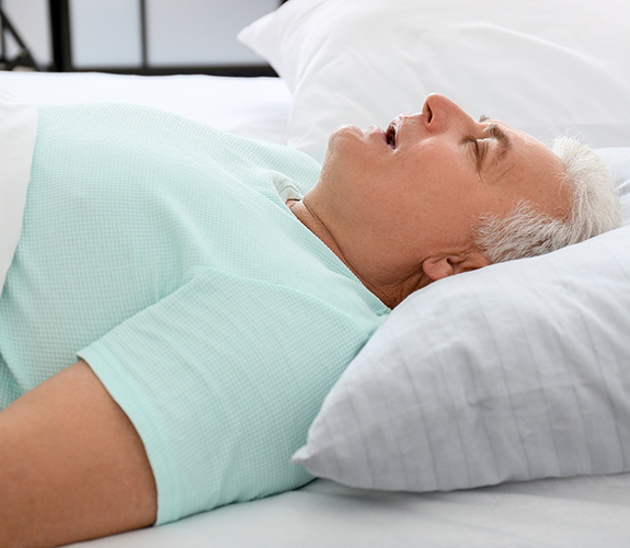 Older man lying in bed snoring