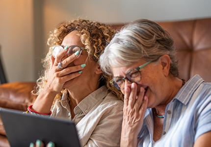 Two women sitting on couch laughing