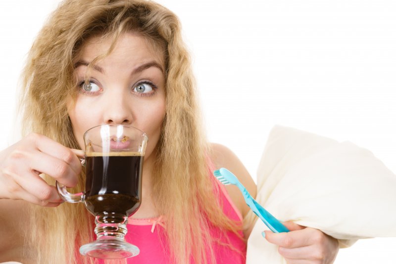woman drinking coffee and holding a towel and toothbrush