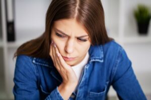 Young woman holding her face in pain