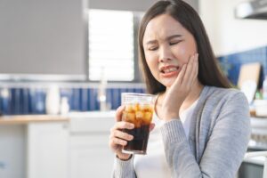 Woman holding a beverage and bothered by tooth pain